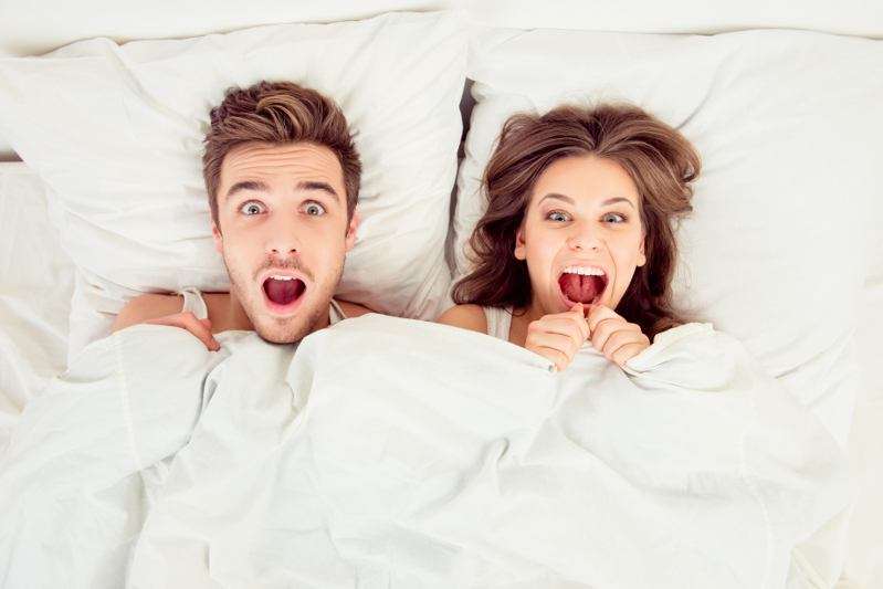 Surprised married couple lying in bed