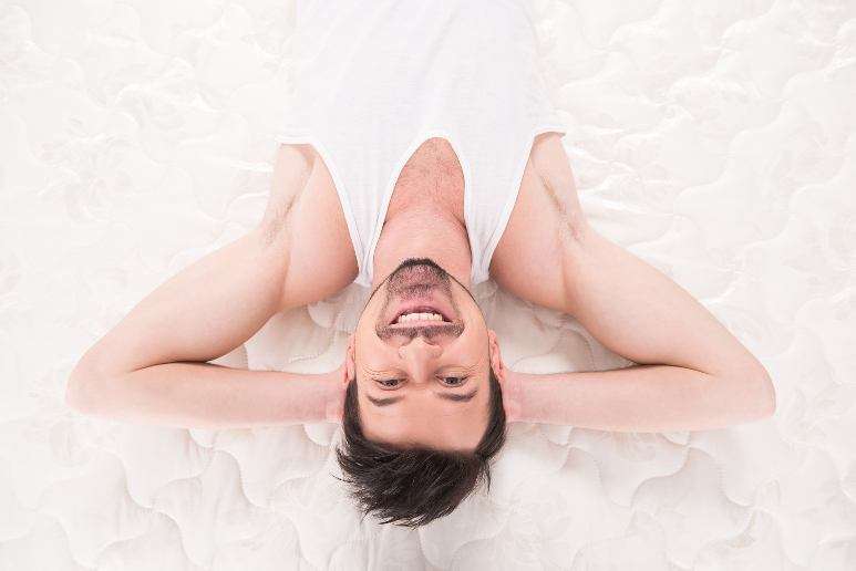 Smiling man lying on truck bed mattress