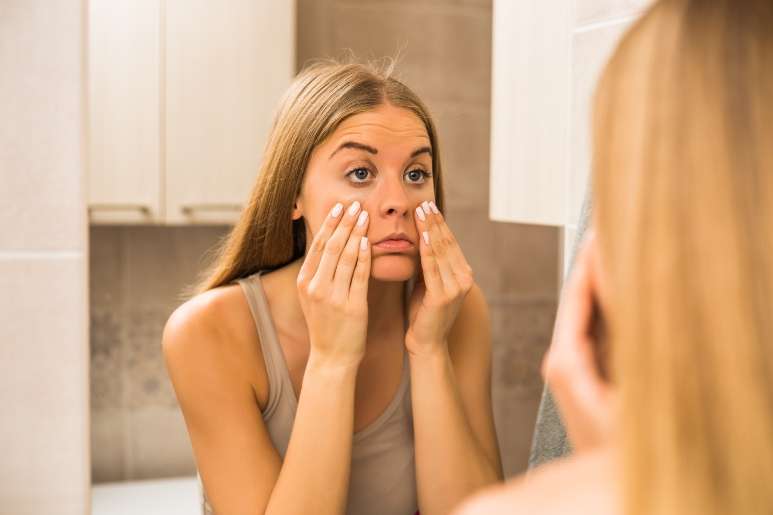Sleep deprived woman looking in mirror